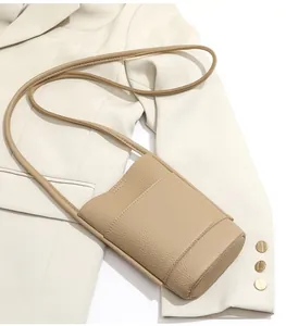 Detail of khaki pebbled leather mini crossbody bag with front pocket on blazer