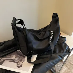Black nylon crescent crossbody bag with branded FASHION strap on a leather jacket