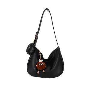 Black crescent canvas shoulder bag with plush charm and small round coin purse accessory
