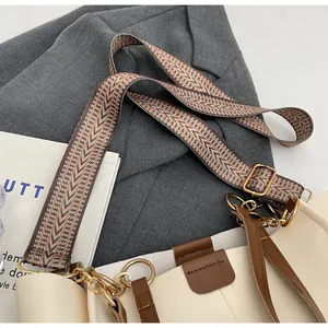 Detail of bohemian geometric woven shoulder strap and cream faux leather handbag
