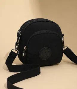 Detail van zwarte nylon crossbody tas met drie ritsvakken en sportief logo erop