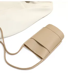 Close-up of beige pebble leather phone bag with front pocket on a neutral blazer background