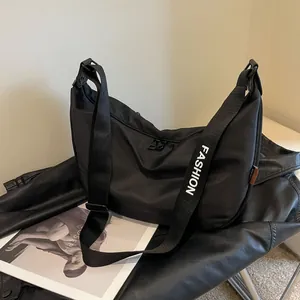 Black nylon crescent crossbody bag with white FASHION lettering on the wide shoulder strap