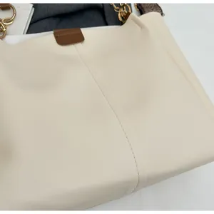 Detailed shot of beige PU leather handbag with gold chain handle and jacquard strap