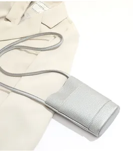 Detail of silver crossbody phone bag with pebble leather texture on a beige blazer