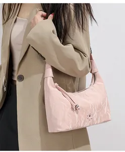 Detail view of pink wrinkled hobo bag with flower pendant on khaki blazer outfit