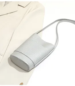 Detail of silver crossbody phone bag with lychee texture on a beige blazer
