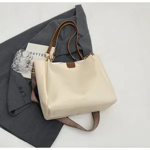 Detail of off-white leather tote bag featuring golden hardware and vintage woven strap