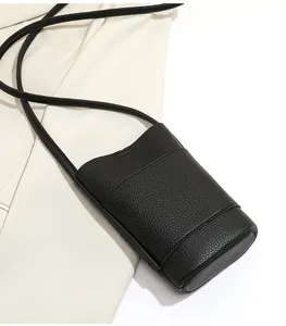 Detail of black lychee grain leather mini crossbody bag with fine stitching and strap