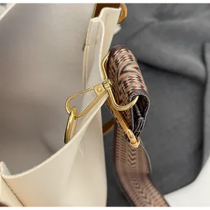 Detail of cream leather tote with golden hardware and ethnic geometric woven shoulder strap