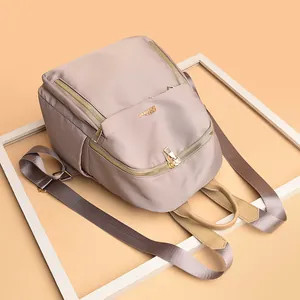 Fashionable nylon women's backpack in pale pink with gold logo on white backdrop