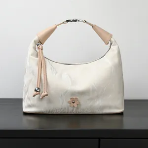 Elegant off-white dumpling handbag with marble texture and delicate floral accent piece