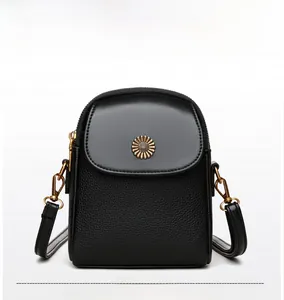 Détail d'un sac bandoulière en cuir noir avec logo marguerite en métal doré