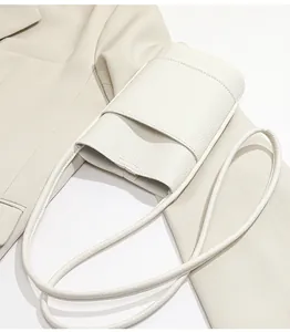 Close-up of white lychee texture crossbody phone bag on a cream blazer background