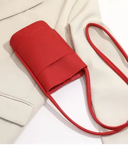Detail of red pebbled leather mini crossbody bag placed on a white suit jacket
