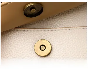 Détail du fermoir magnétique en bronze sur sac bandoulière en cuir grainé bicolore