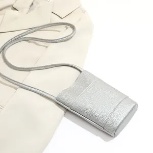 Silver mini crossbody phone bag in pebble faux leather on a beige blazer background