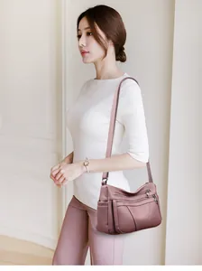 Detail of pink soft leather crossbody bag with multiple zippers and wide strap on model