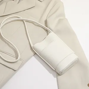 White minimalist lychee pattern mini crossbody cell phone bag on beige blazer