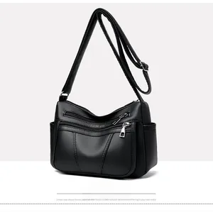 Detail of black pebbled leather crossbody bag with multiple zip pockets and adjustable strap
