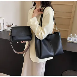Detail of black leather tote bag set with metal ring hardware and woven shoulder strap