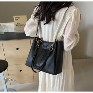 Detailed back view of a black leather tote bag with woven strap on model's shoulder