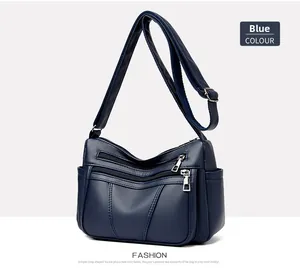 Detail of dark blue soft faux leather handbag with multiple zipper pockets and adjustable strap