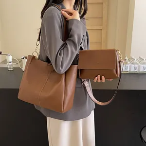 Brown two-piece tote bag set with jacquard strap and small crossbody bag on table