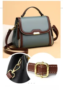Detail of grey-blue pebble leather bag with brown trim and golden metal hooks