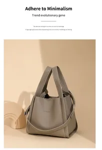 Detalle del bolso tipo cubo de cuero gris granulado con asa gruesa y hebilla lateral
