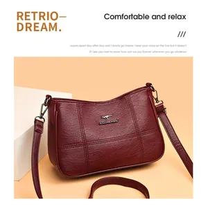 Detailed close-up of wine red leather crossbody bag with refined pebble texture and metallic logo