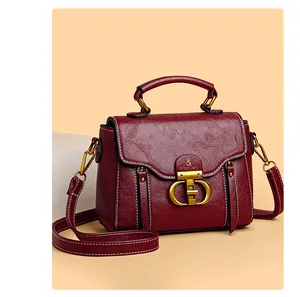 Detailed close-up of burgundy leather crossbody bag with gold twist lock and white stitching