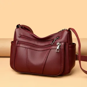 Burgundy faux leather shoulder bag with multi-layer zippers and adjustable strap
