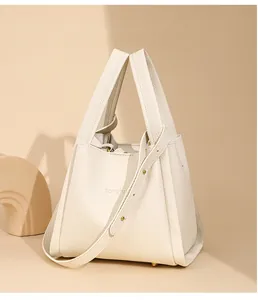 Primer plano del bolso saco de cuero crema con textura granulada y tacos metálicos de base