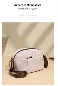 Close-up of cream crossbody bag with soft pleats and dark brown wide fabric strap