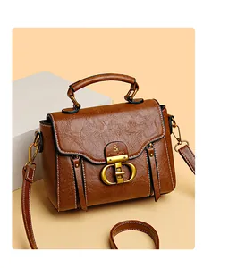 Detail of soft brown pebble leather handbag with gold D-buckle and white contrast stitching