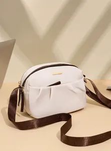 Detail of waterproof nylon crossbody bag with pleated pocket and golden metal bar