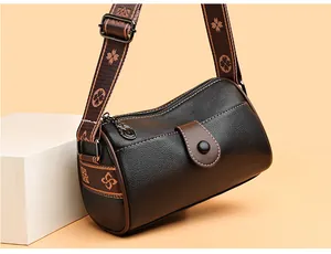 Détail du sac bandoulière cylindrique noir avec sangle tissée aux motifs floraux