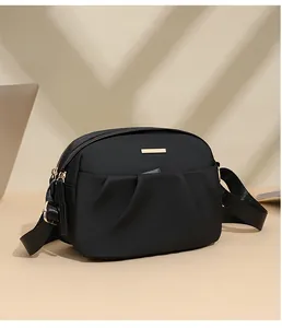 Close-up of black oxford crossbody bag featuring golden hardware and dual zipper texture