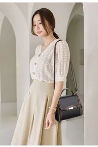 Detail of a dark brown leather crossbody bag with gold hardware and stylish side zippers