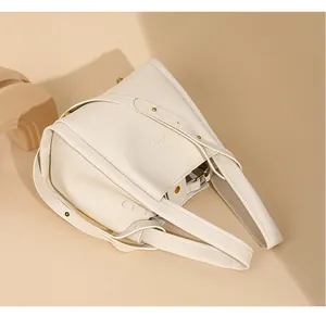 Detalle de bolso de mano en cuero granulado blanco con acabados metálicos en dorado