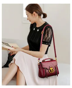 Detail view of burgundy leather handbag with gold metal clasp and textured finish