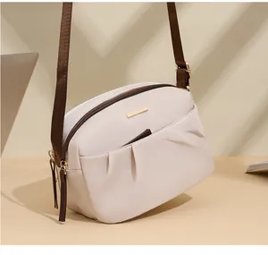 Detail of waterproof nylon crossbody bag with gold hardware and wide brown strap