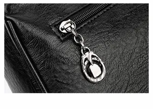 Detailansicht des verzierten silbernen Metallreißverschlusses an der schwarzen Ledertasche