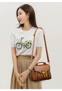 Detail view of a vintage brown leather crossbody bag with a golden metal buckle and logo