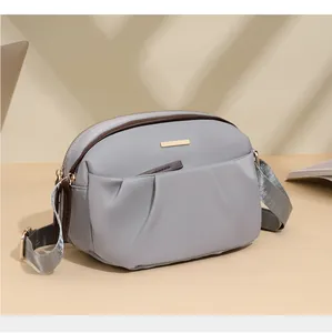 Detail view of water-resistant oxford fabric crossbody bag with golden metal plaque