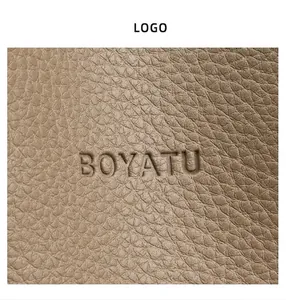 Primer plano de cuero granulado y logotipo de BOYATU grabado en el bolso