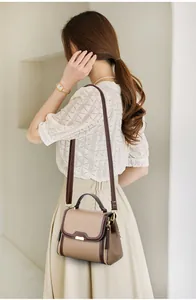Detail of vintage textured leather crossbody bag with contrasting brown edges on a model