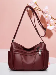 Detailansicht der weinroten Schultertasche aus Leder mit mehreren Reißverschlüssen