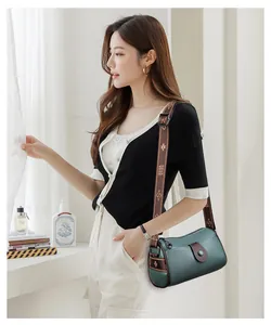 Détail du sac bandoulière en cuir vert foncé avec large sangle à motif floral